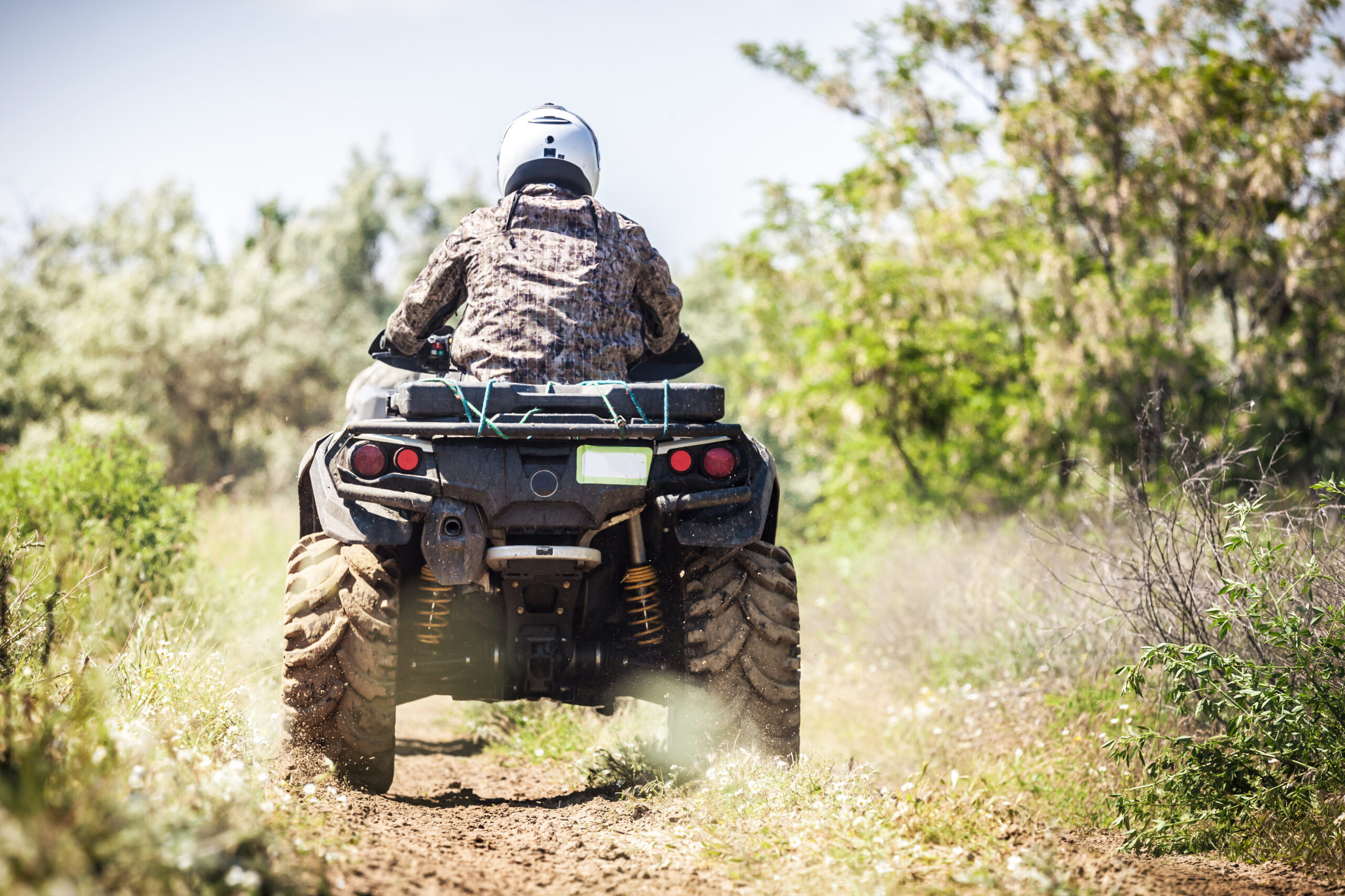Back view of quad bike zipping along a country road.