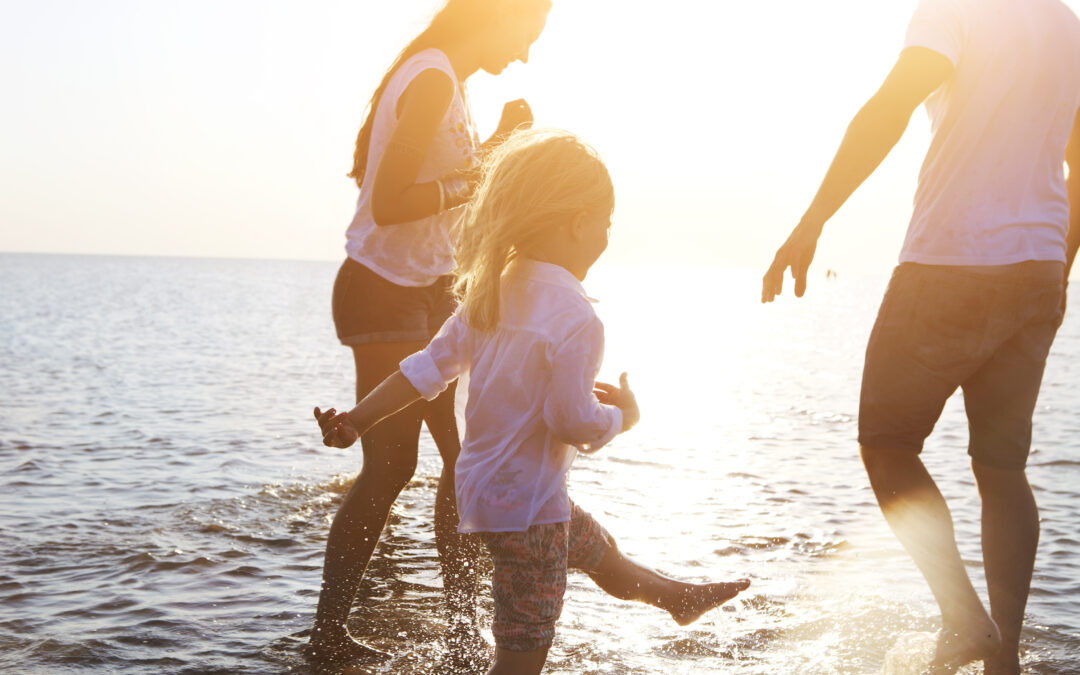 Happy young family having fun running on beach at sunset. Family traveling concept